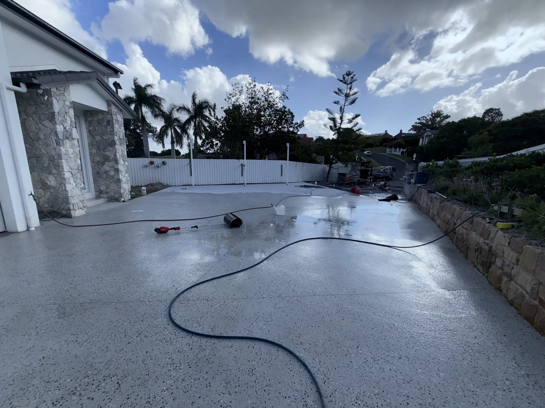 Freshly washed pool surround beside a stone-clad house